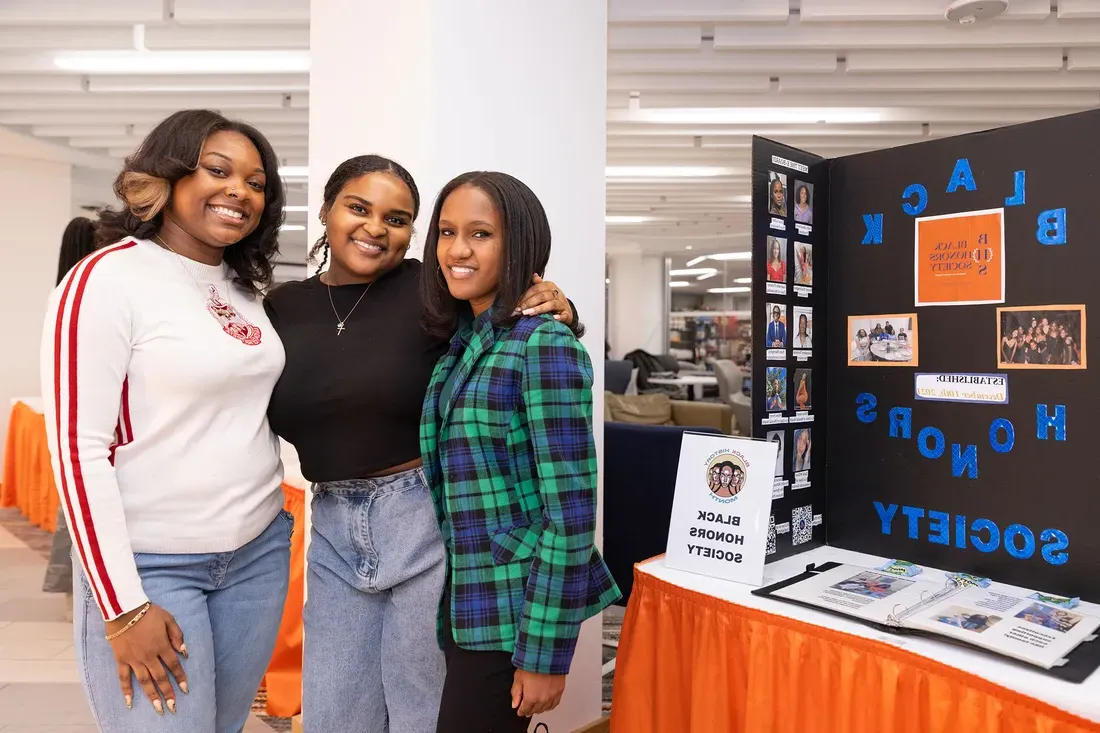 Three people posing together at an information fair.